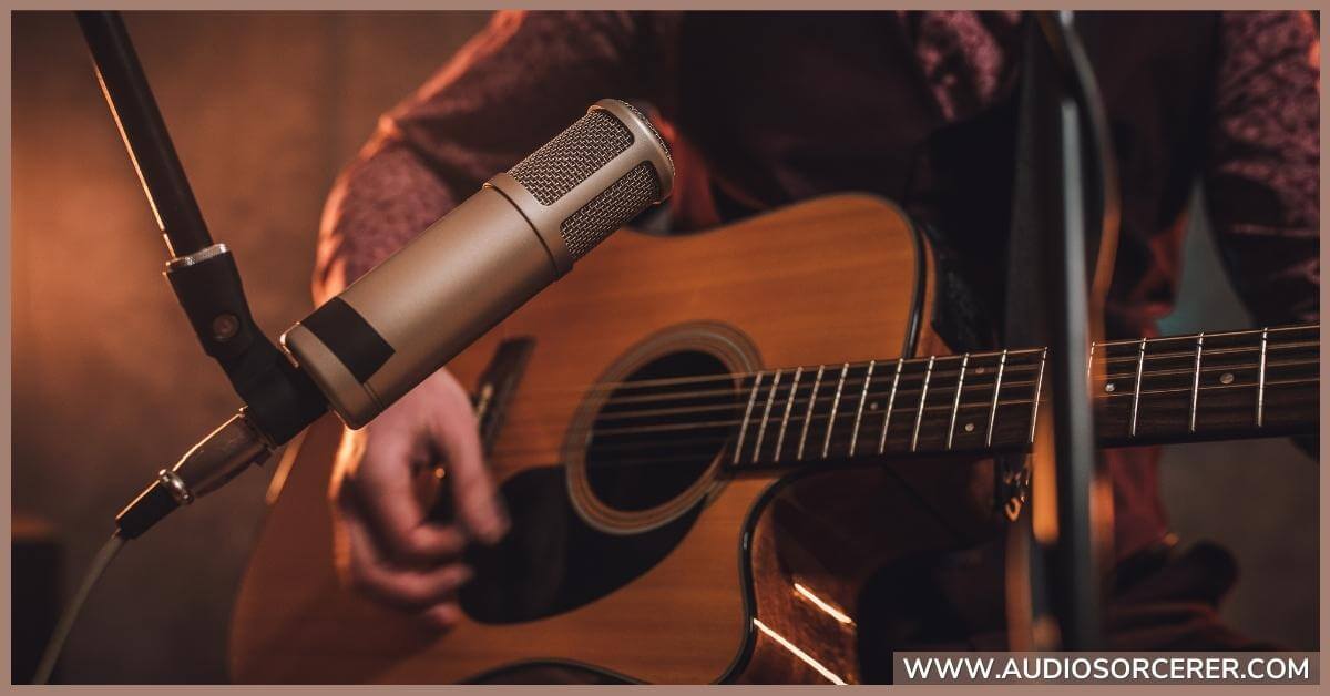 Man recording an acoustic guitar miked with a large diaphragm condenser microphone.