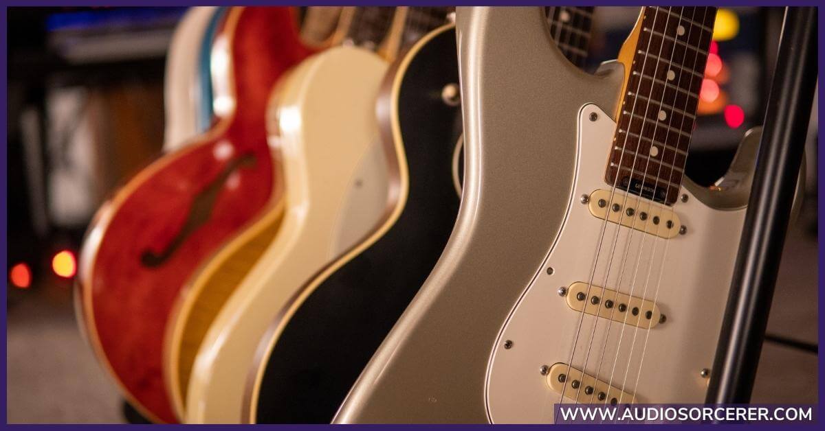 A bunch of different guitars on a rack with a Fender Stratocaster in the forefront.