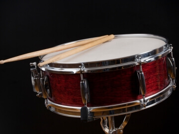 Snare drum with sticks on it.