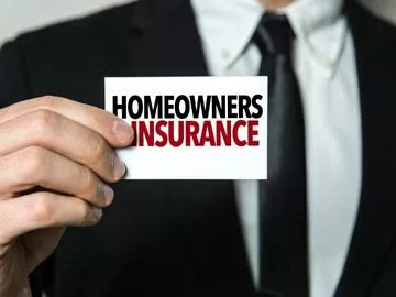 A man holding a card that says "homeowners insurance".