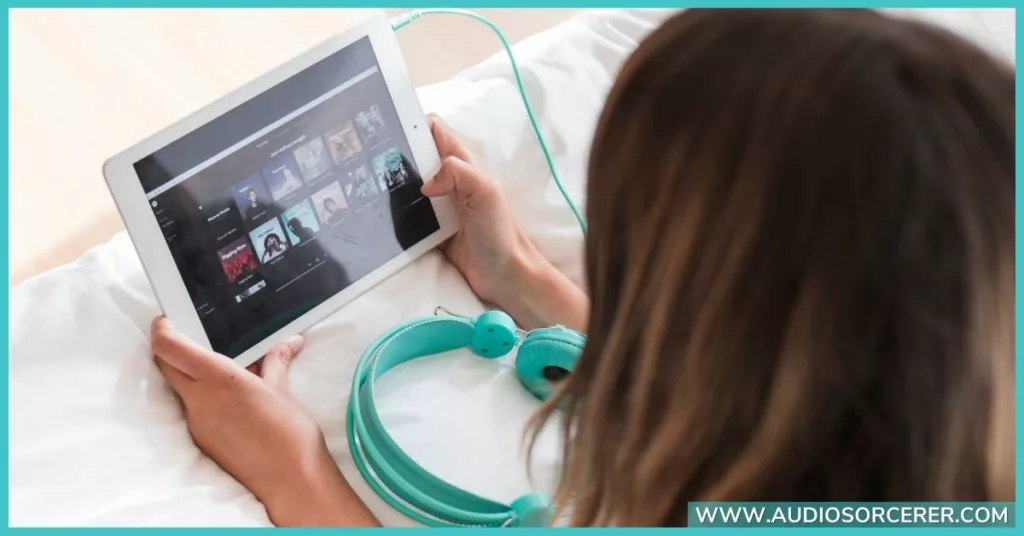 A woman streaming music and listening on turquoise headphones. 