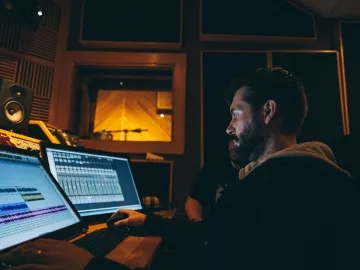 A music producer working with recording equipment and software.