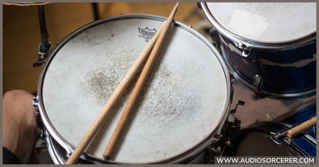 A snare drum with two drum sticks on it.