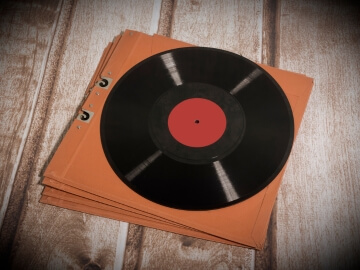 Long Play Vinyl Record sitting on a table on top of an orange sleeve.
