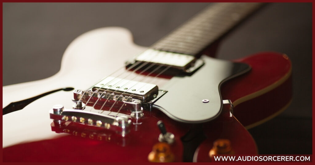 A red electric guitar with a closeup of the strings.