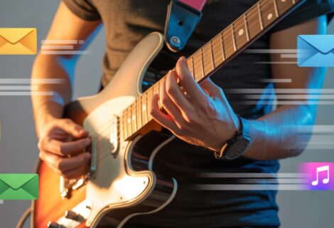 Closeup of a guy playing the electric guitar with emails floating around him representing emailing marketing for musicians.